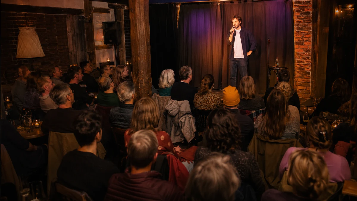 Symbolisches Event-Visual für Stand-up-Comedy oder Solo-Kabarett mit kleiner Bühne und sitzendem Publikum.